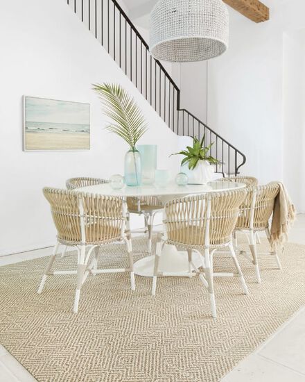 Beachy dining room with white and wicker chairs on a rug of Pleats And Thanks in Beige.